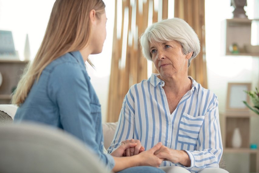 Cuidadora jovem segurando as mãos de idosa num ambiente acolhedor de residência sénior em Sintra