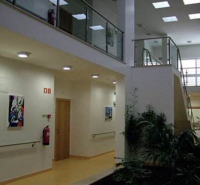 Interior luminoso de residência sénior em Sintra com corredor, arte nas paredes, plantas e escadas com vidro